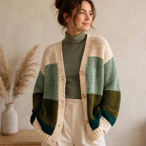 May include: A long-sleeve, button-down crochet cardigan featuring horizontal color-blocked stripes in cream, sage green, olive green, and dark teal. The garment has a V-neckline, ribbed cuffs, and a ribbed hem, worn over a solid olive green turtleneck.