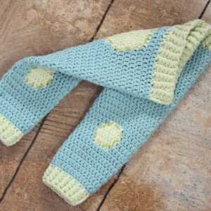 May include: A blue and green crocheted leg warmer with a dotted pattern.