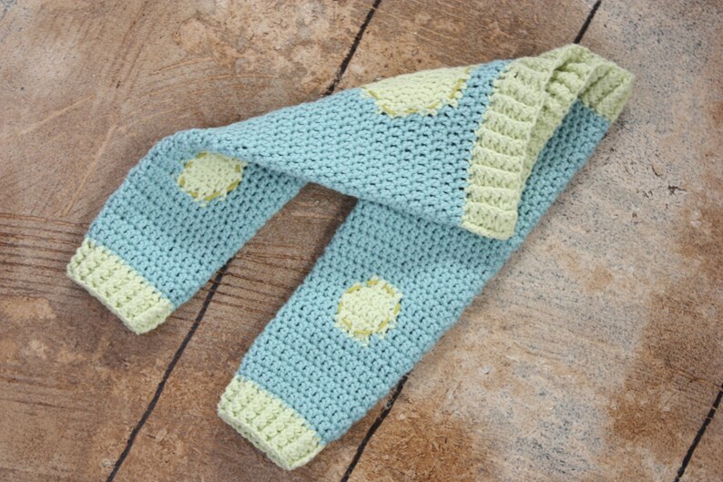 May include: A blue and green crocheted leg warmer with a dotted pattern.