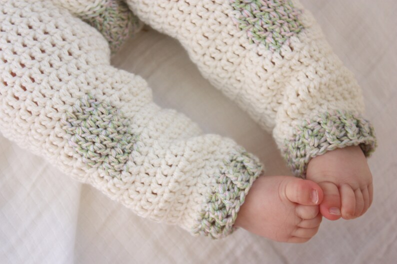 May include: White crocheted baby pants with green and white stripes on the cuffs.