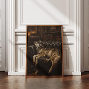 May include: A framed wall art print featuring a dark, moody oil painting of a wolf resting on a tufted leather sofa inside a dimly lit library. The scene includes shelves filled with books and a single glowing candle in the background.