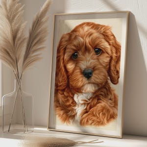 Pode incluir: Uma impressão de arte emoldurada com o retrato de um filhote de cachorro fofo, de cor castanho-avermelhada, com grandes olhos escuros e uma mancha branca no peito. O filhote tem pelos longos e ondulados e um nariz preto, em moldura dourada.
