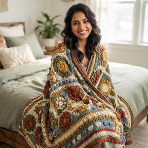 May include: A handmade crochet blanket featuring a repeating granny square pattern in earthy tones of mustard yellow, sage green, terracotta orange, and cream. The textile displays intricate floral-inspired circular motifs and textured stitches.