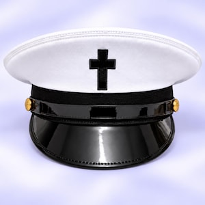 May include: A white peaked cap featuring a black cross emblem centered on the front crown. The hat includes a black band, a glossy black patent visor, and two small gold-toned buttons on the sides securing a thin black chin strap across the front.