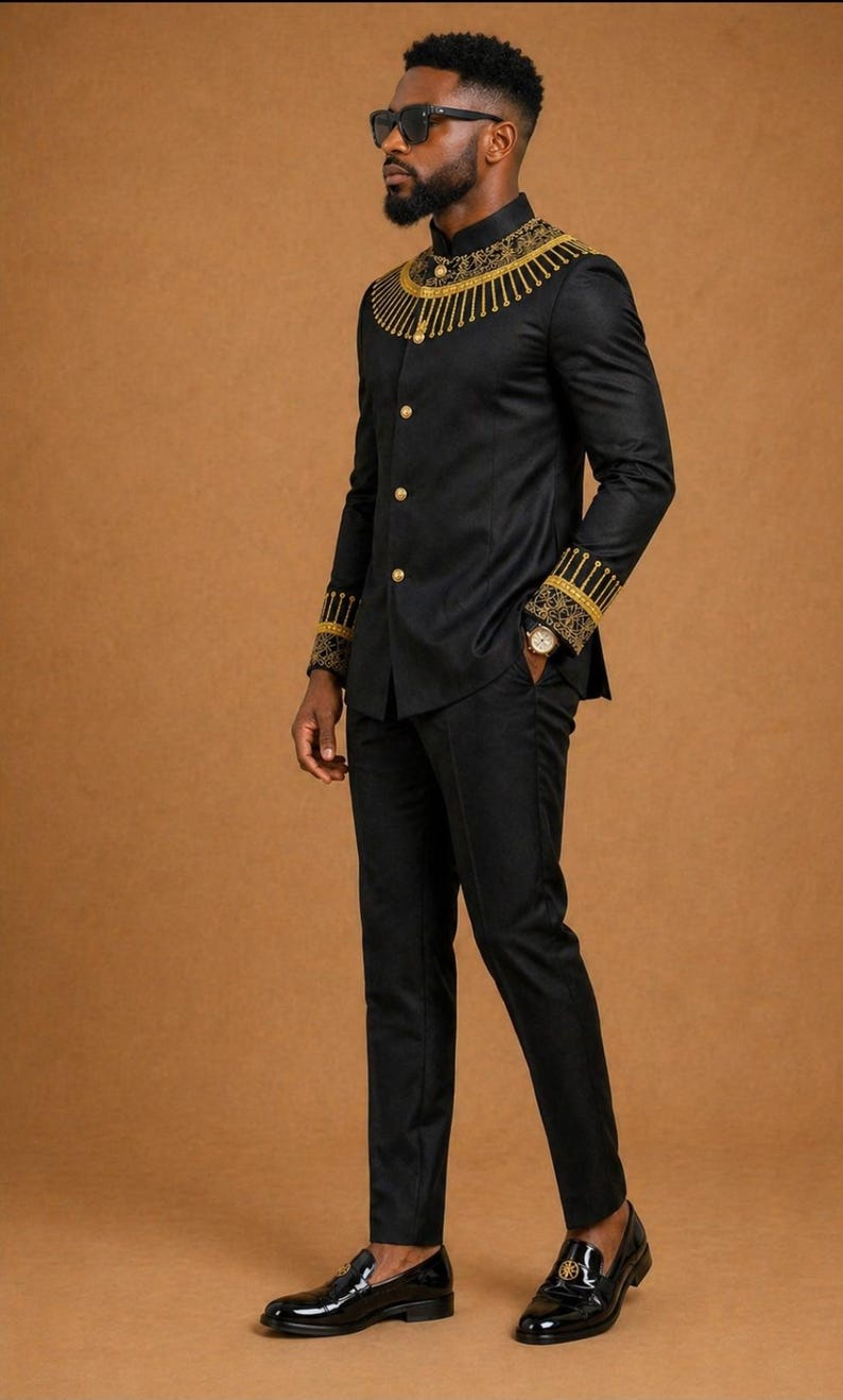 K&ouml;nnte beinhalten: Ein schwarzes Set aus lang&auml;rmeliger Jacke und passender Hose. Die Jacke hat einen Stehkragen mit goldener Stickerei, goldene Kn&ouml;pfe und gold gemusterte Manschetten. Das Ensemble wird mit schwarzen Slippern und einer Sonnenbrille kombiniert.