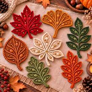 May include: A collection of seven crocheted leaf ornaments in various shapes and autumn colours including red, orange, yellow, green, and cream. Each leaf features intricate raised rope-like textures and small gold beads embedded throughout the design.