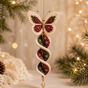 May include: A hanging ornament featuring a crocheted butterfly top with cream, dark red, and green embroidery, attached to a spiraling, twisted fabric tail in matching red and green with gold snowflake patterns, finished with a clear crystal drop.