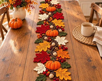 May include: A crochet table runner featuring a repeating pattern of orange pumpkins, red, yellow, green, and cream-colored autumn leaves, small brown acorns, and clusters of red berries arranged along a dark brown vine-like central structure.