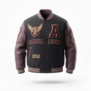 May include: A charcoal grey varsity jacket with dark maroon leather sleeves. The front features a winged lion crest, the letter A, the text ACADIA LIONS, and the year 1952. The jacket has a snap-button closure and striped ribbed trim on the collar, cuffs, and hem.