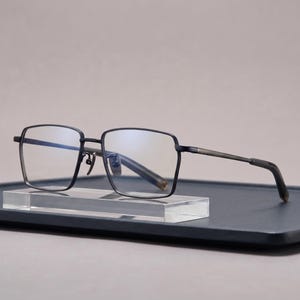 Black titanium eyeglasses front view, a lightweight square optical frame for men with a thin flat-top brow bar and clear non-prescription lenses worn as everyday business glasses.
