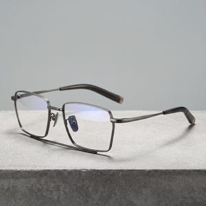 Gunmetal grey titanium frames for men, a minimalist square eyeglasses frame front view with blue light blocking clear demo lenses and adjustable metal nose pads for office glasses wear.