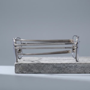 Gunmetal grey titanium frames side profile, a folded square optical frame revealing spring barrel hinges, acetate temple tips and diamond-knurled engraving along this lightweight men's eyeglasses arm.