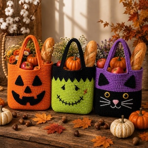 May include: Three crocheted tote bags featuring Halloween designs: an orange jack-o'-lantern, a lime green monster with a stitched mouth, and a purple and black cat face. Each bag contains a baguette, a small pumpkin, and colorful flowers.