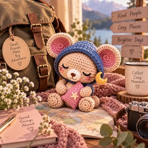 May include: A crocheted mouse toy with a blue hood, pink ears, and a small yellow crescent moon accessory, holding a pink star-patterned pillow. The scene includes a brown backpack with a wooden tag, a pink notebook, and a white mug with text.