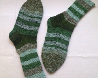 May include: A pair of green, blue, and brown striped socks. The socks are made of a soft, knitted fabric.
