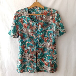 May include: A teal and orange short-sleeved button-up blouse with a colorful abstract print featuring figures and geometric shapes.