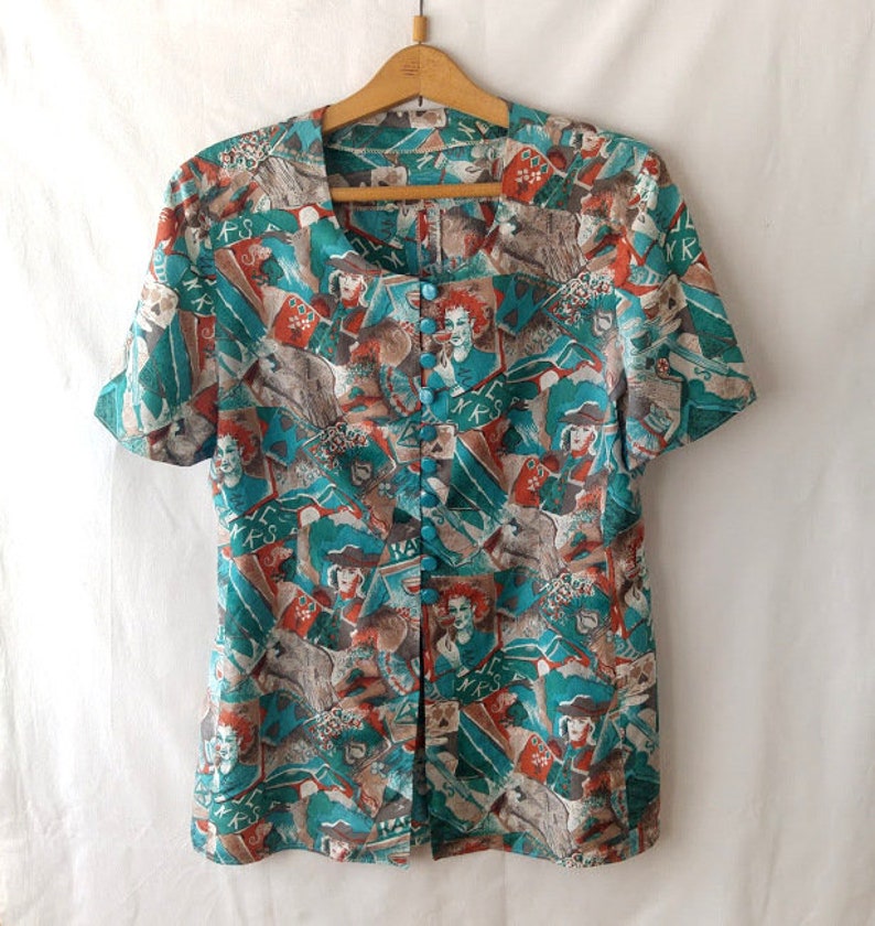 May include: A teal and orange short-sleeved button-up blouse with a colorful abstract print featuring figures and geometric shapes.