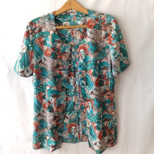 May include: A teal and orange button-up shirt with a short sleeve and a colorful abstract print. The print features various figures and patterns.