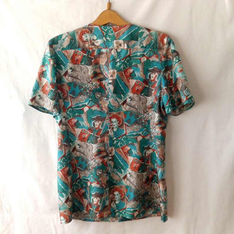 May include: A teal and orange short-sleeved button-up shirt with a colorful abstract print featuring faces and the word "MKS".