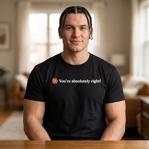 Peut inclure: Un t-shirt noir à manches courtes arborant une petite icône orange en forme de soleil sur la poitrine gauche, suivie du texte blanc "You're absolutely right!" imprimé dans une police sans empattement au centre de la poitrine.