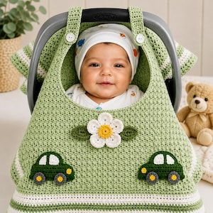 May include: A sage green crocheted car seat cover featuring two dark green car appliques, a central white flower with a yellow center, and two white horizontal stripes at the bottom. The cover attaches to the handle with two white buttons.