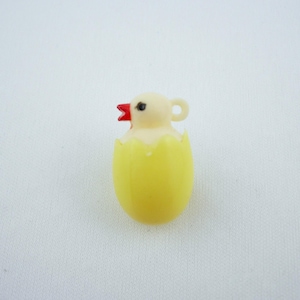 Puede incluir: Un pequeño pollito amarillo saliendo de un huevo amarillo. El pollito tiene una cabeza color crema, un pico rojo y un ojo negro. El huevo está agrietado, revelando el pollito en su interior. El fondo es una superficie blanca lisa.