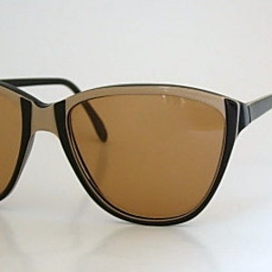 May include: A pair of brown cat-eye sunglasses with a black frame and brown lenses.