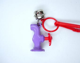 Campana de plástico con dije de grifo de agua vintage morado y rojo auténtico, estilo kitsch nostálgico de los años 80.