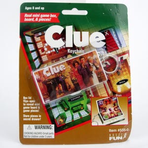 May include: A Clue keychain on a cardboard backing. The keychain features a miniature game board and characters from the classic mystery game. The packaging includes text that reads "Ages 8 and up" and "Real mini game box, board, & pieces!"
