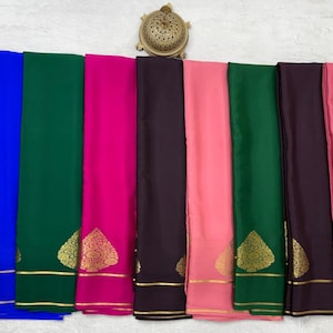 May include: A collection of nine folded fabric panels in red, blue, green, magenta, dark brown, light pink, dark green, purple, and pink. Each panel features a gold-colored metallic leaf-shaped motif and two horizontal gold-colored stripes.