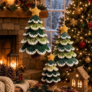 Può includere: Tre decorazioni natalizie all'uncinetto a forma di albero di varie dimensioni, con rami a strati verde scuro e chiaro, bordi smerlati bianchi e una piccola stella gialla in cima, appese a sottili cordini di spago marrone.