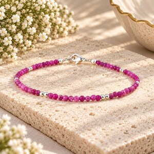Può includere: Un braccialetto delicato con piccole perline sfaccettate color rosa magenta alternate a perline sferiche argentate lucide. Il braccialetto è fissato con una chiusura a moschettone argentata, creando un gioiello raffinato ed essenziale.