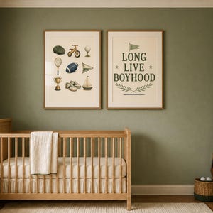 May include: Two framed wall art prints hanging above a wooden crib. The left print features illustrations of a cap, tricycle, golf tee, tennis racket, football, pennant, trophy, shoes, and sailboat. The right print displays the text LONG LIVE BOYHOOD.