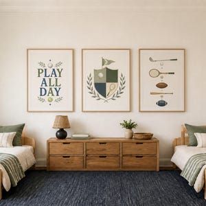 Puede incluir: Tres l&aacute;minas de pared enmarcadas con temas deportivos, que incluyen un cartel con el texto PLAY ALL DAY, un emblema de escudo con una pelota de golf y una raqueta de tenis, y una colecci&oacute;n de diversos equipos deportivos como un palo de golf.