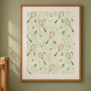 A framed watercolor tennis racket pattern print hangs on a sage green wall above a wooden crib.