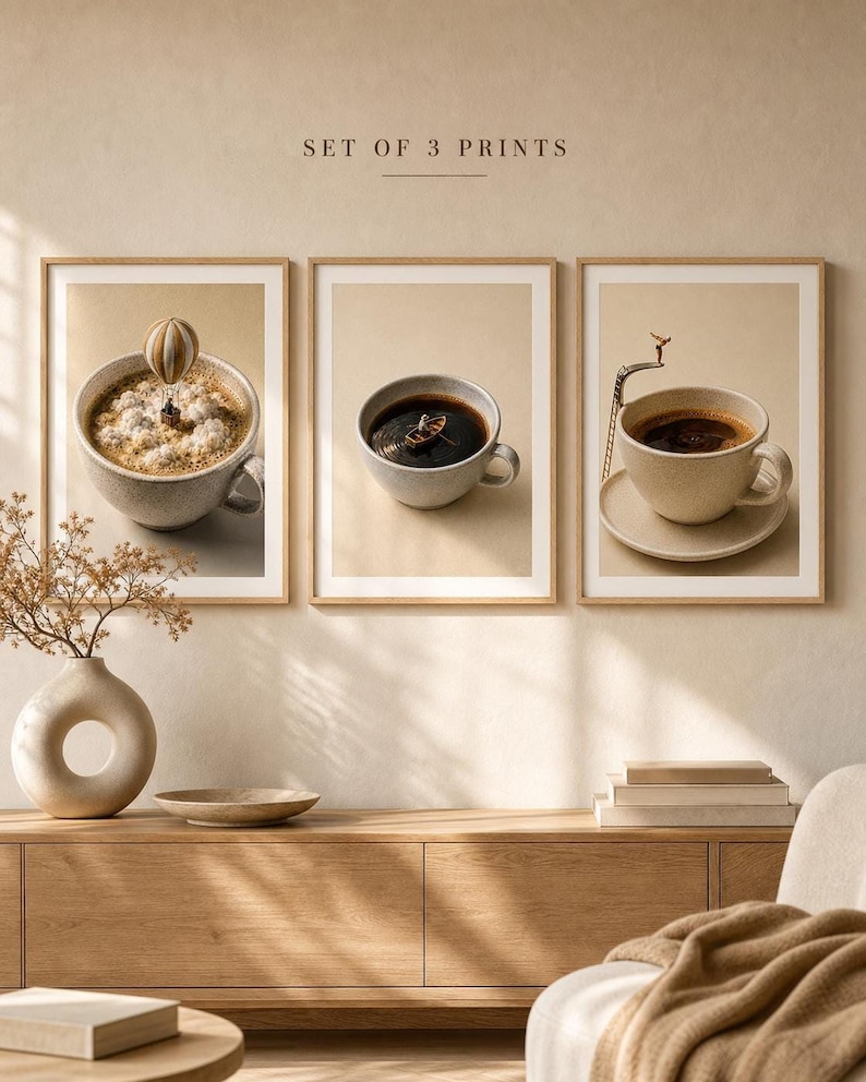 A mockup showing three framed art prints of coffee-themed miniature photography hanging above a wooden console table with a vase of dried stems and stacked books.