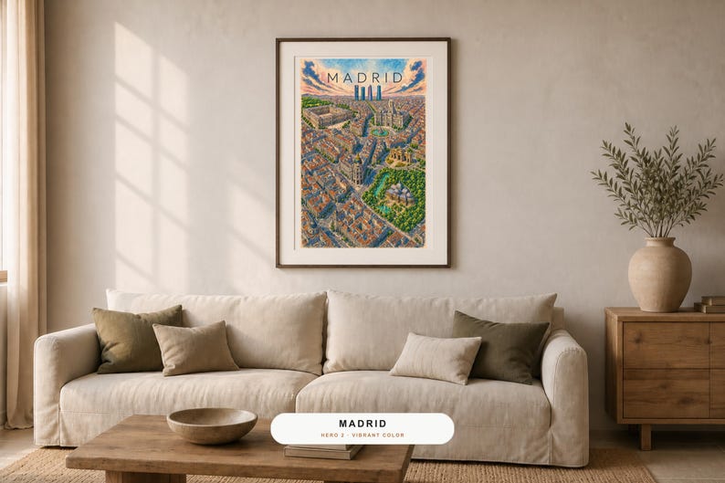 May include: A framed vertical art print featuring a detailed, colorful aerial illustration of the city of Madrid, Spain. The artwork displays dense urban architecture, green park spaces, and a skyline under a blue sky with the text MADRID.