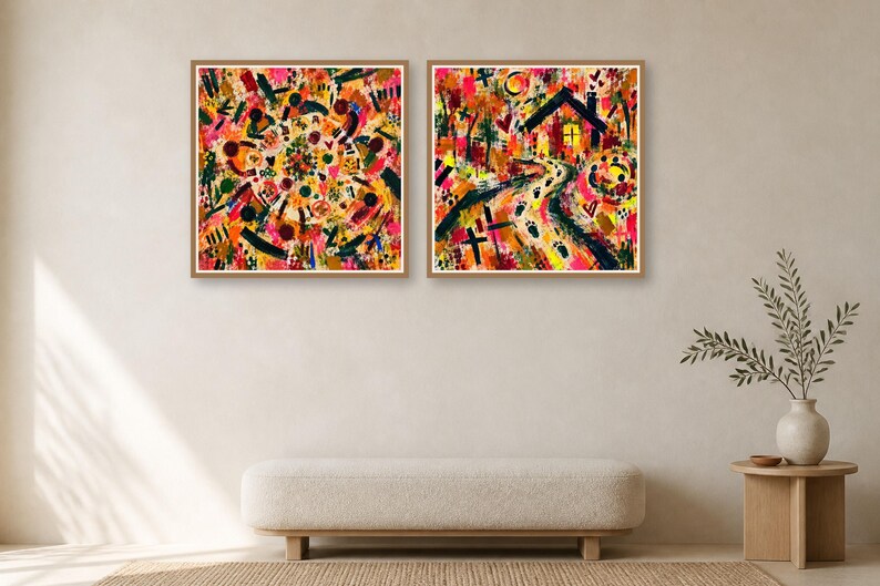 Two square framed abstract art prints hanging side by side on a neutral wall above a tufted bench and a wooden side table with a plant.
