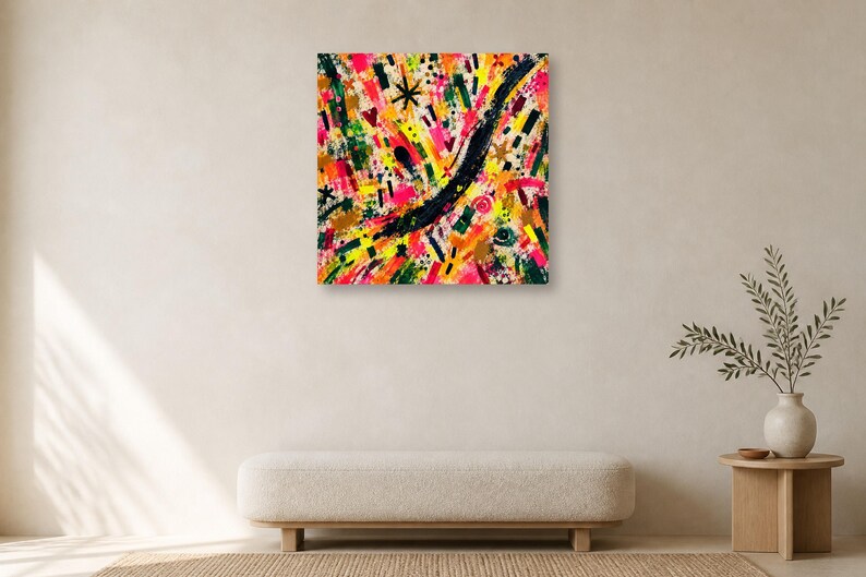 A square abstract art print featuring colorful gestural brushstrokes hangs centered on a plain wall above a low cream bench.