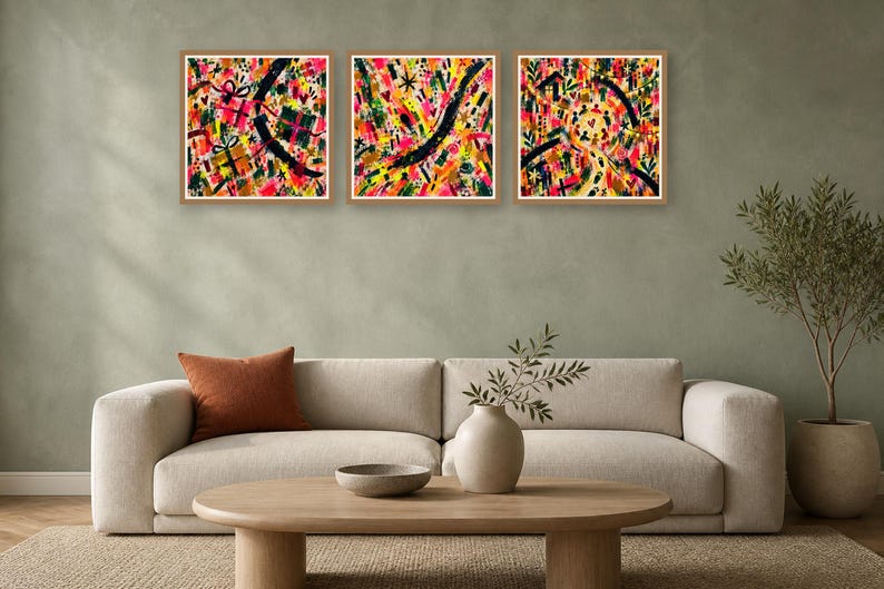 Living room interior featuring a beige sofa, wooden coffee table, and three square colorful abstract artworks hung on a sage green wall, showing different prints.
