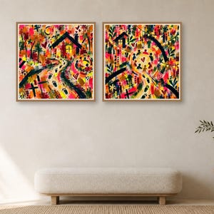 Two framed square abstract art prints displayed side by side on a neutral wall above a long bench and side table.