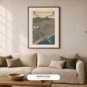 May include: A framed vertical wall art print featuring an illustrated aerial map of Barcelona, Spain. The artwork displays the city grid, coastline, and landmarks in muted tones of blue, beige, and dark green, with the word BARCELONA at the top.
