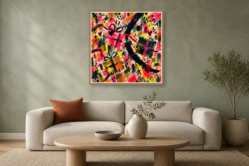 A wood-framed square abstract art print with vibrant brushstrokes hangs above a neutral sofa on a green wall.
