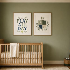 May include: Two framed wall art prints featuring sports themes. The left print displays the text PLAY ALL DAY in blue and green with a golf ball and tennis ball. The right print features a shield crest with a golf ball, tennis racket, and flag.