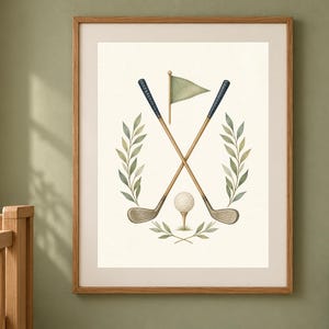 May include: A framed wall art print featuring a watercolor illustration of two crossed golf clubs, a golf ball on a tee, and a small flag, all centered within a symmetrical arrangement of green leafy branches on a cream-colored background.