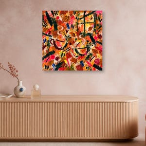 A square abstract wall art print hangs on a light pink wall above a long wooden credenza with ceramic vases.