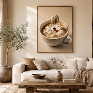 Framed wall art depicting a coffee cup with a hot air balloon floating above foam clouds, displayed above a sofa in a living room.