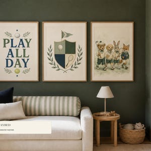May include: Three framed wall art prints displayed above a daybed. The first print features the text PLAY ALL DAY with a golf ball and tennis ball. The second shows a crest with a golf ball and racket. The third depicts a bear, dog, rabbit, and fox.