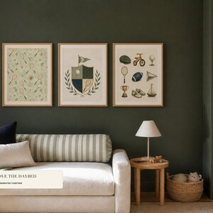 Three framed art prints featuring a sports pattern and vintage icons hung above a modern sofa against a dark green wall.