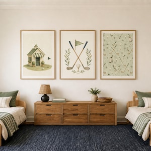 May include: Three framed wall art prints featuring golf-themed illustrations. The left print shows a small clubhouse, the center print displays crossed golf clubs with a flag and ball, and the right print features a repeating pattern of golf gear.